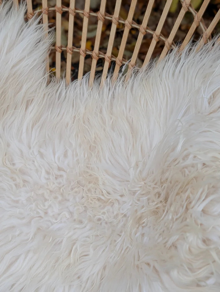 A plush natural white icelandic sheepskin rug with long wool and soft curly texture perfect for cozy spaces