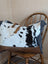 A white and black cowhide duffle bag with tan leather straps and brown embossed leather base from angus oliver affair canvas hair