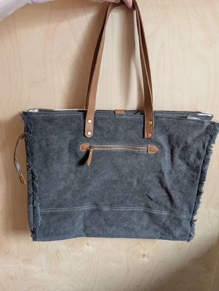 Gray matty affair canvas weekender bag with frayed edges tan leather handles and zipper accents by angus oliver