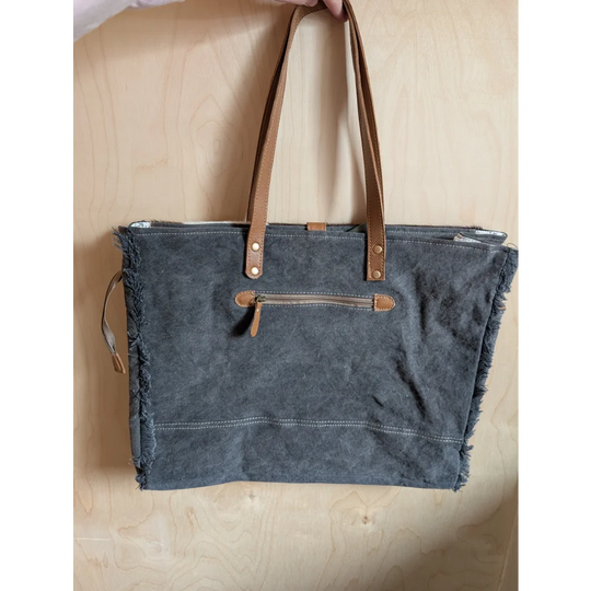 Gray matty affair canvas weekender bag with frayed edges tan leather handles and zipper accents by angus oliver