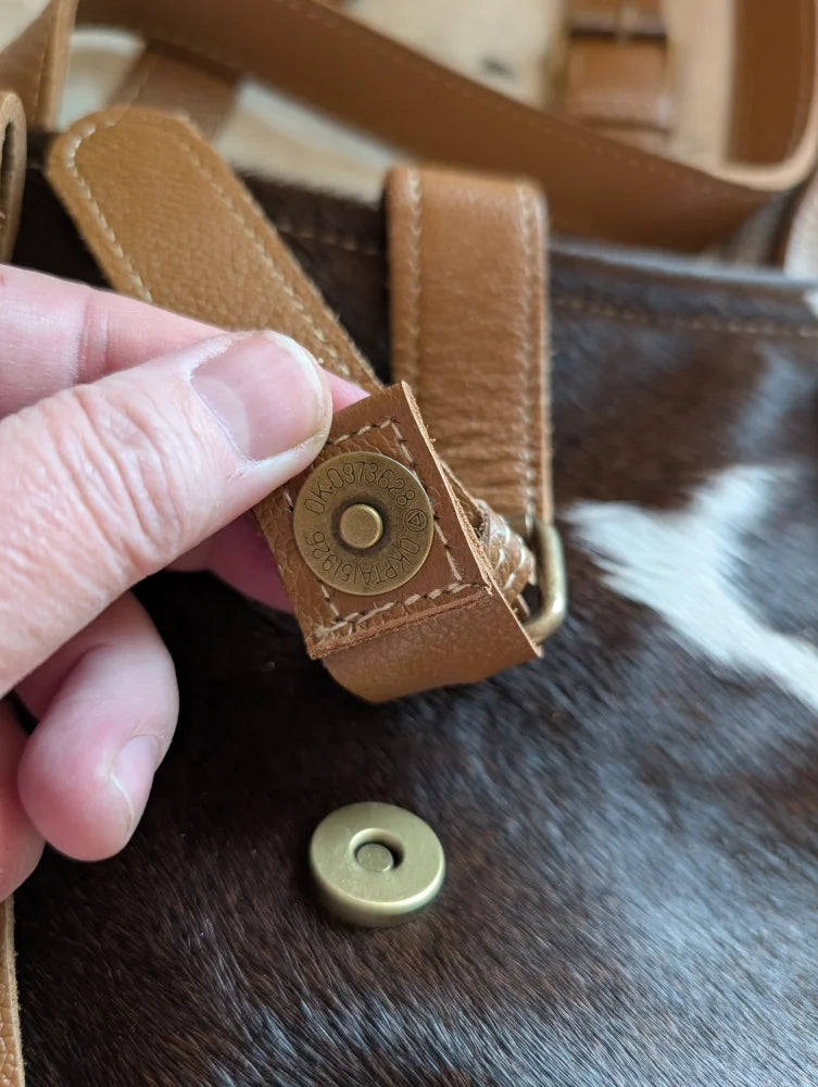 Tan leather strap with brass magnetic snap closure on the #6 matty affair canvas hair weekender bag by angus oliver