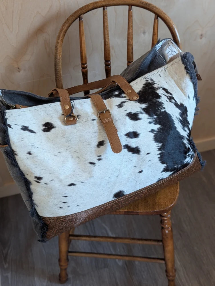 Black and white cowhide matty affair canvas tote bag with tan leather straps and brown embossed trim by angus oliver