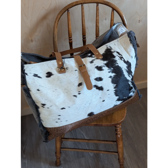 Black and white cowhide matty affair canvas tote bag with tan leather straps and brown embossed trim by angus oliver