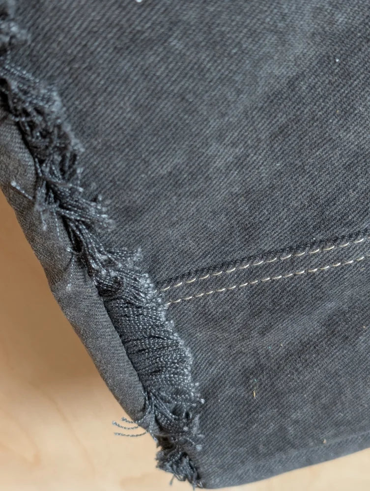 Dark gray denim fabric with frayed edges and white stitching on matty affair canvas weekender bag by angus oliver