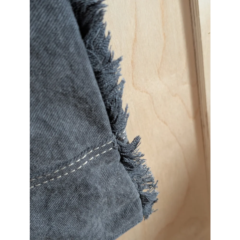 Dark gray denim fabric with frayed edges and white stitching on angus oliver matty affair canvas weekender bag