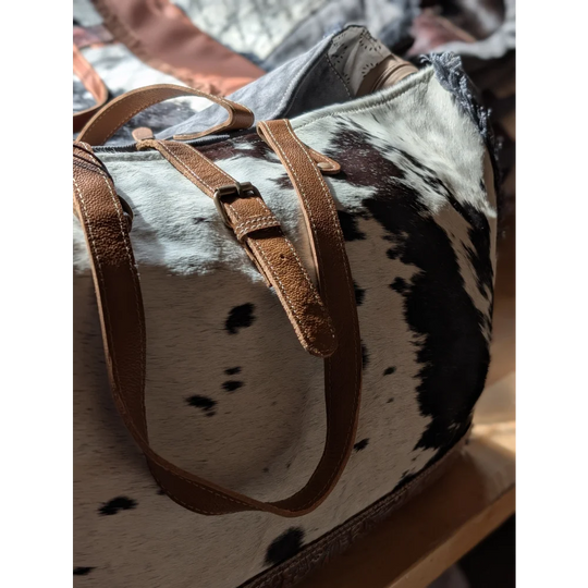 A matty affair canvas hair cowhide duffle bag with brown leather straps and black and white spotted angus oliver pattern