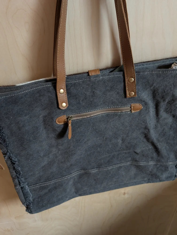 Dark blue denim weekender bag with brown leather straps and zipper accents made from matty affair canvas by angus oliver