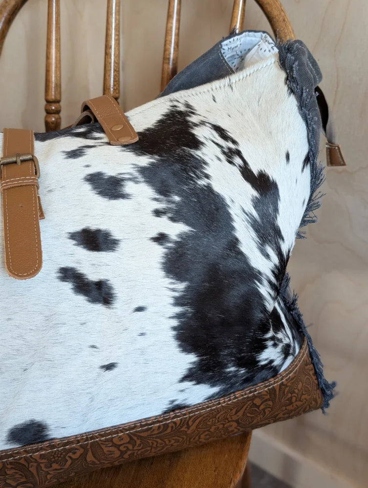Black and white cowhide affair canvas hair tote bag with tan leather straps and brown embossed trim by angus oliver