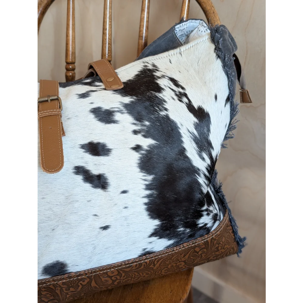 Black and white cowhide affair canvas hair tote bag with tan leather straps and brown embossed trim by angus oliver