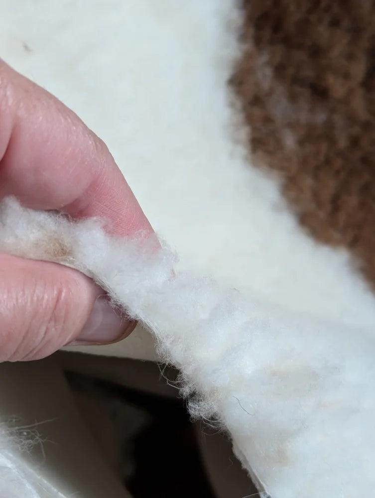 White fluffy cotton batting held between fingers from grade a- highland spotted sheepskin product