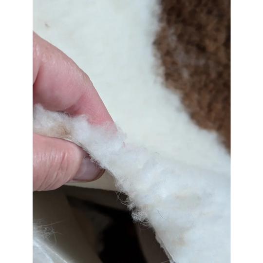 White fluffy cotton batting held between fingers from grade a- highland spotted sheepskin product