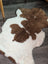 A plush irregular highland spotted grade a- sheepskin rug with natural brown and white cow print pattern