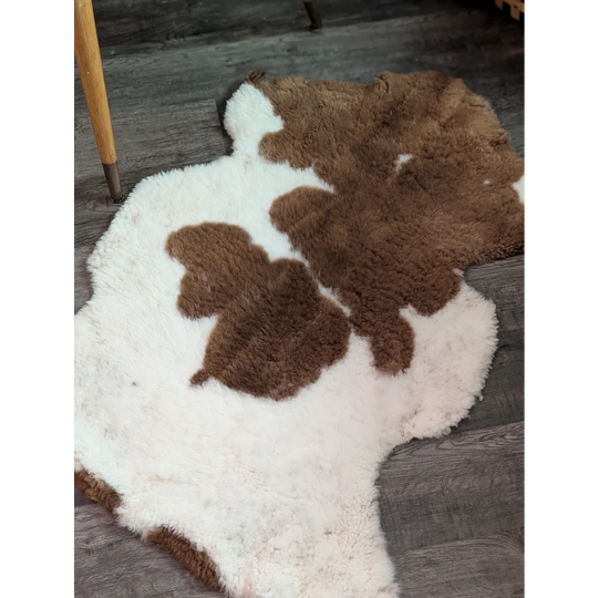 A plush irregular highland spotted grade a- sheepskin rug with natural brown and white cow print pattern