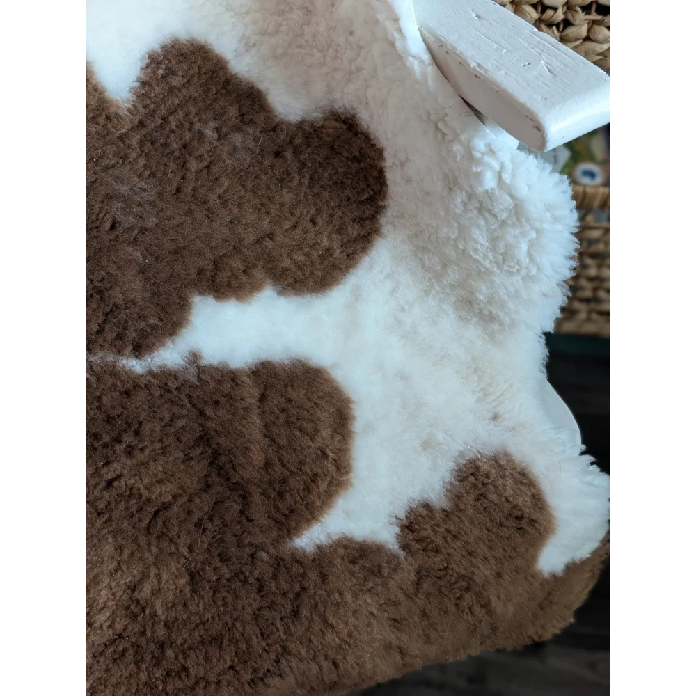 A plush brown and white cow print throw blanket made from grade a- highland spotted sheepskins with a fluffy texture