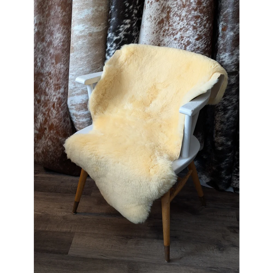 Cream-colored 42x27 British Medical Sheepskin throw with wooden legs