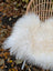 Large long wool natural white icelandic sheepskin draped over a wicker chair for cozy decor and comfort