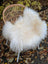 White fluffy large long wool icelandic sheepskin chair cover draped over natural white wicker chair