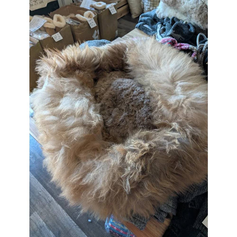 Cozy sheepskin pet bed with natural fur texture in earthy brown tones