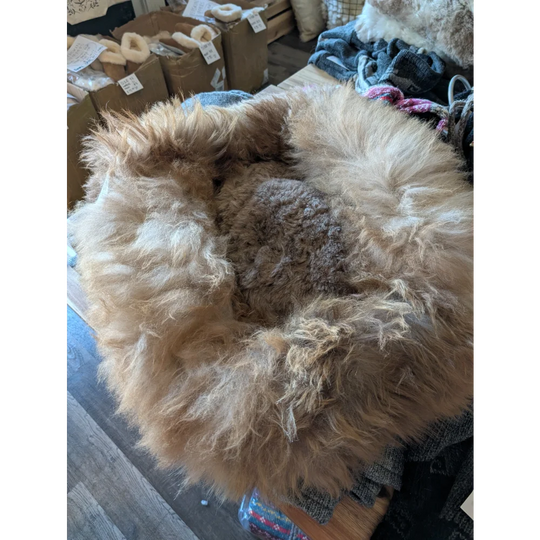 Cozy sheepskin pet bed with natural fur texture in earthy brown tones