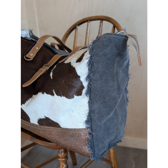Brown and white cowhide matty affair canvas weekender bag with tan leather straps and distressed denim side panel