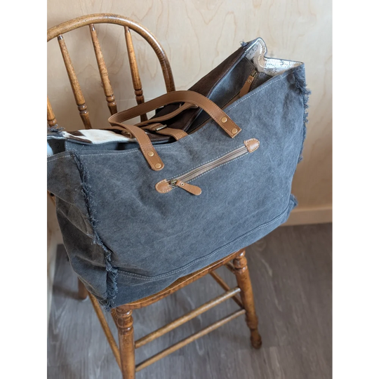 Blue denim matty affair canvas weekender bag with tan leather handles and zipper accents by angus oliver