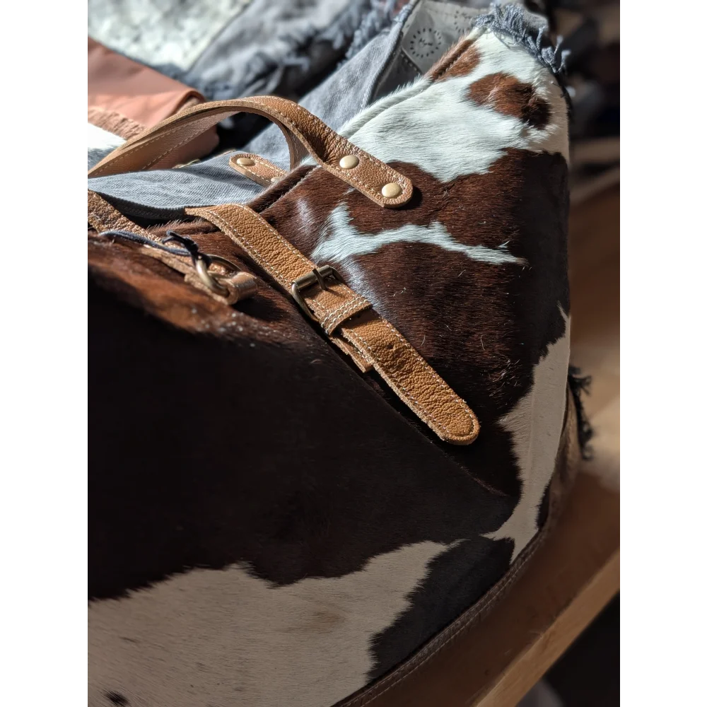 Brown and white cowhide duffle bag with tan leather straps and brass hardware from the matty affair canvas line