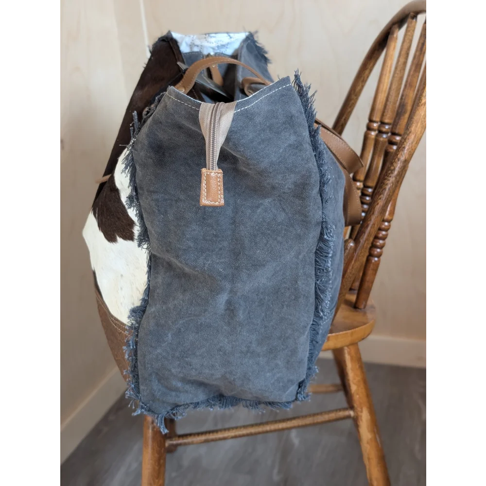 A distressed denim tote bag with frayed edges and tan leather handles from the angus oliver matty affair canvas line