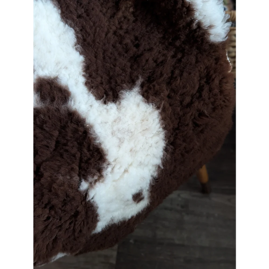 A plush brown and white highland spotted sheepskin chair cover with soft fluffy texture grade a- sheepskins