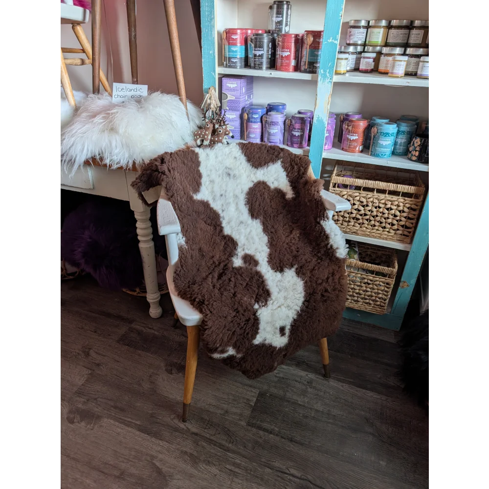 Brown and white highland spotted sheepskin grade a- rug draped over chair showcasing soft natural wool texture