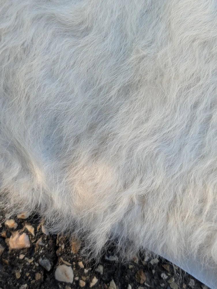 A large cowhide style soft fluffy white faux fur blanket with dense wavy texture perfect for unique beautiful rugs