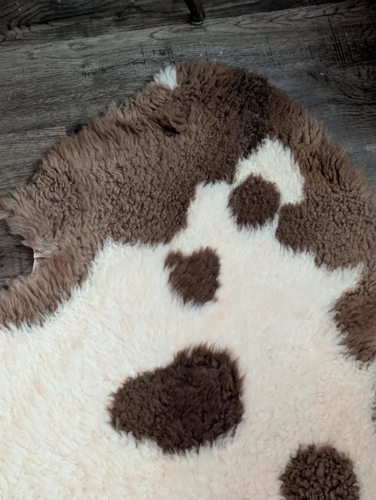 A plush cream and brown highland spotted grade a- sheepskin rug with soft fluffy texture perfect for cozy decor
