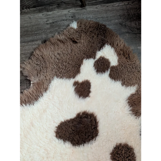 A plush cream and brown highland spotted grade a- sheepskin rug with soft fluffy texture perfect for cozy decor