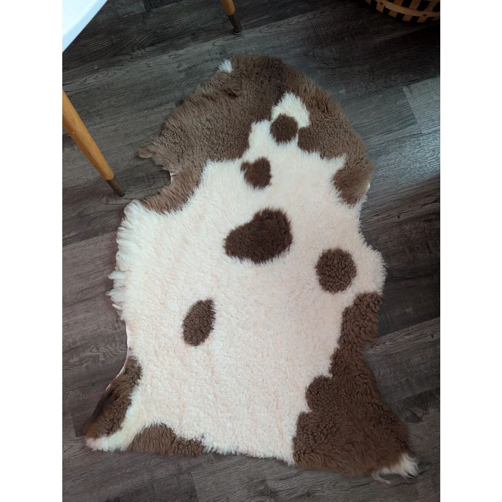 A plush grade a- highland spotted sheepskin rug with natural white and brown cow-print pattern