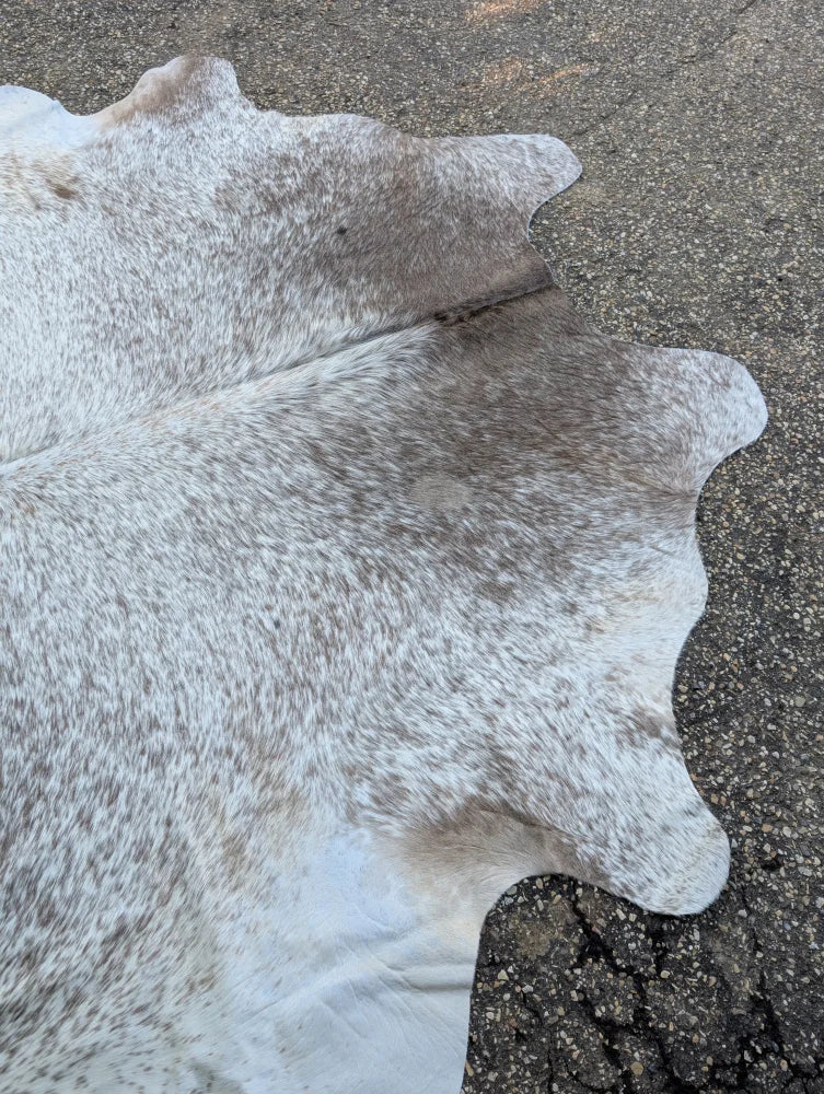 Large 89 x 77 grey mix cowhide rug with white and gray speckles and a natural edge showing unique characteristics and rustic charm