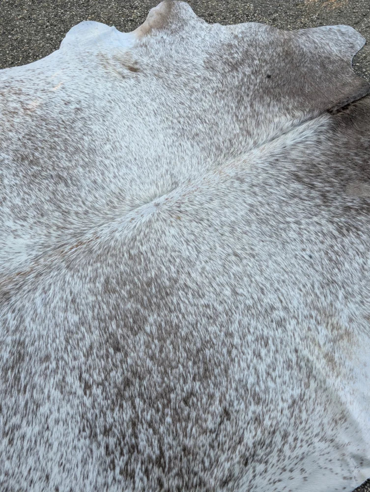 Large cowhide rug with unique characteristics in a mottled white and gray pattern adding rustic charm to any room