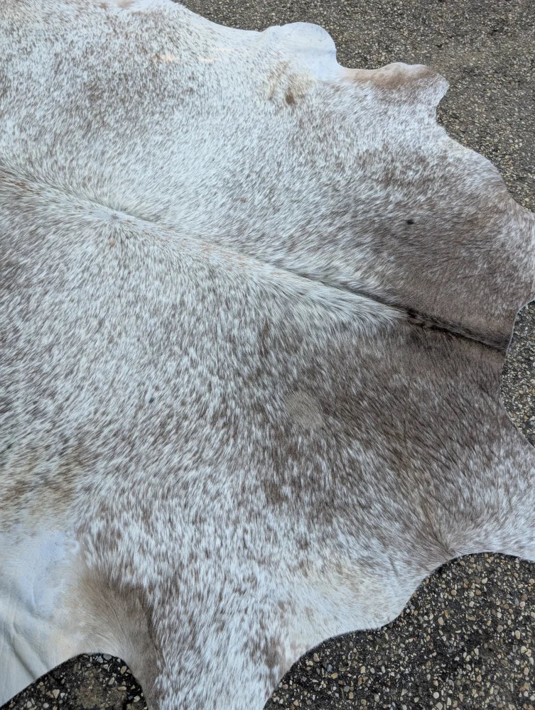 A large cowhide rug in grey mix with unique characteristics and rustic charm featuring a soft textured surface