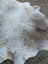 A large cowhide rug in grey mix with unique characteristics and rustic charm featuring a soft textured surface