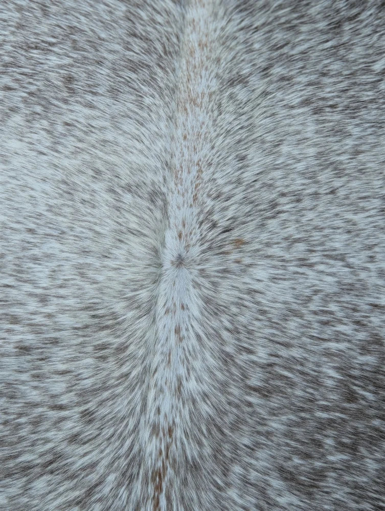 Large gray and white speckled cowhide rug with unique characteristics and rustic charm measuring 89 by 77 inches