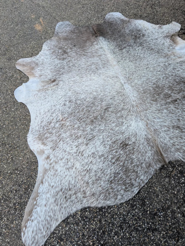 Large cowhide rug with unique irregular shape and rustic charm in a grey and white mottled pattern 89 x 77 inches