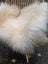 A plush cream-colored natural white icelandic sheepskin long wool throw draped over a wicker chair