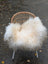 A cozy natural white icelandic sheepskin throw with long wool draped over a woven wicker chair with metal legs