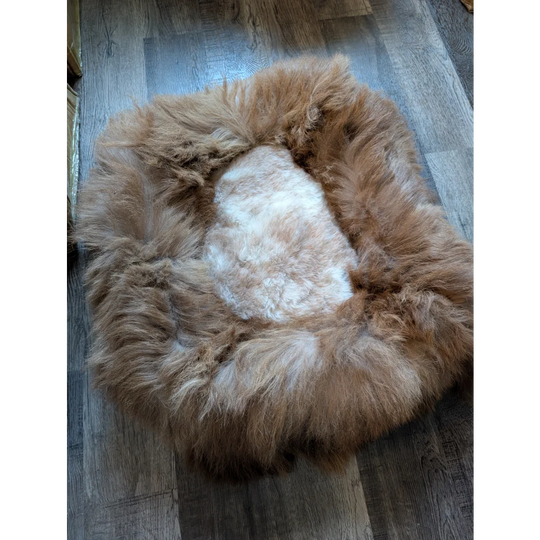 Cozy highland sheepskin pet bed with plush white interior and light brown faux fur exterior