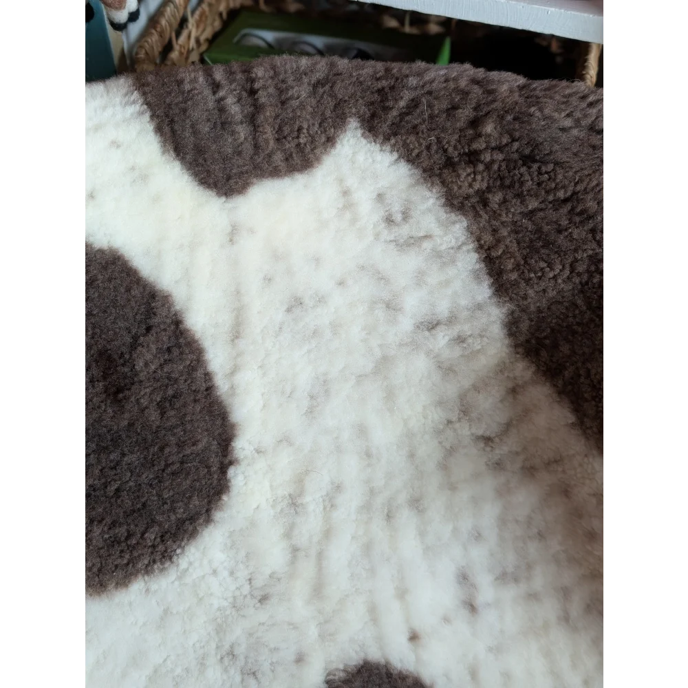 A plush white and brown highland spotted grade a- sheepskin rug with soft texture and cow pattern