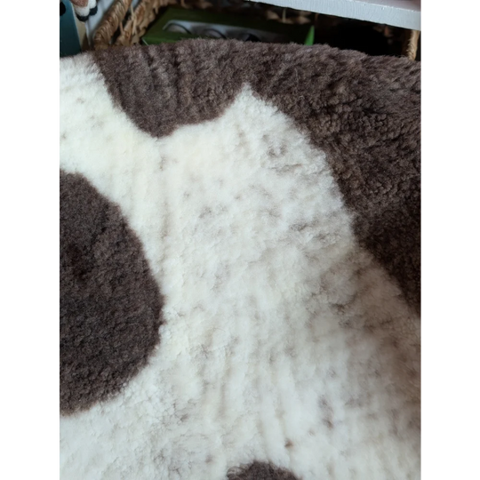 A plush white and brown highland spotted grade a- sheepskin rug with soft texture and cow pattern