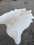 Large cowhide rug with natural white and beige tones and soft fluffy texture offering rustic charm and unique characteristics