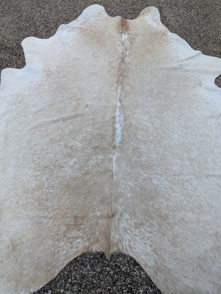 A large cowhide rug 92 x 81 with natural off-white color and subtle tan markings showcasing unique characteristics and rustic charm