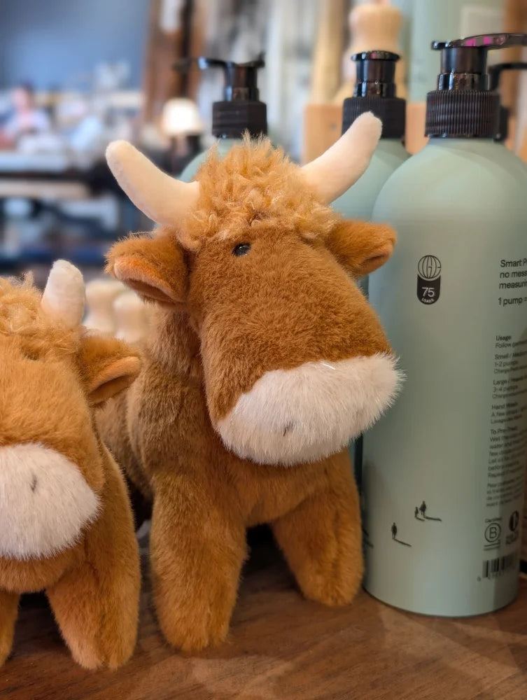 A plush brown highland cow stuffed toy with white horns and fluffy white muzzle perfect for cuddling