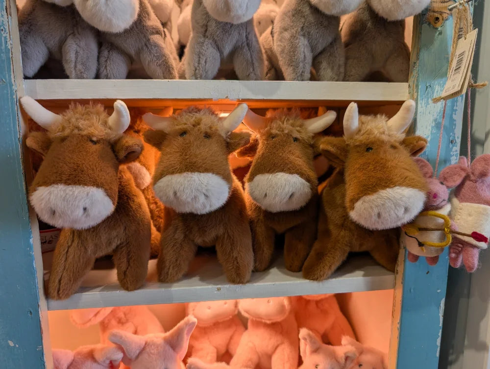 Adorable brown highland cow stuffed animals with white snouts horns and soft head fluff displayed in a row
