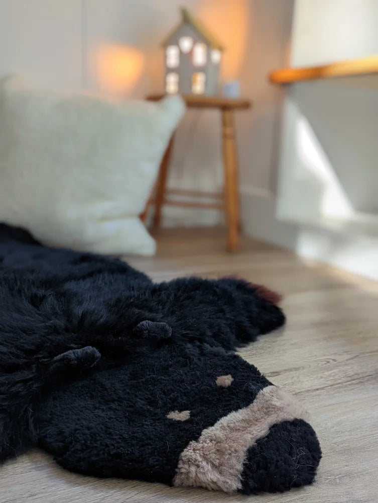 Adorable merino sheepskin black bear rug with black faux fur and beige accents on snout and paws mid october style