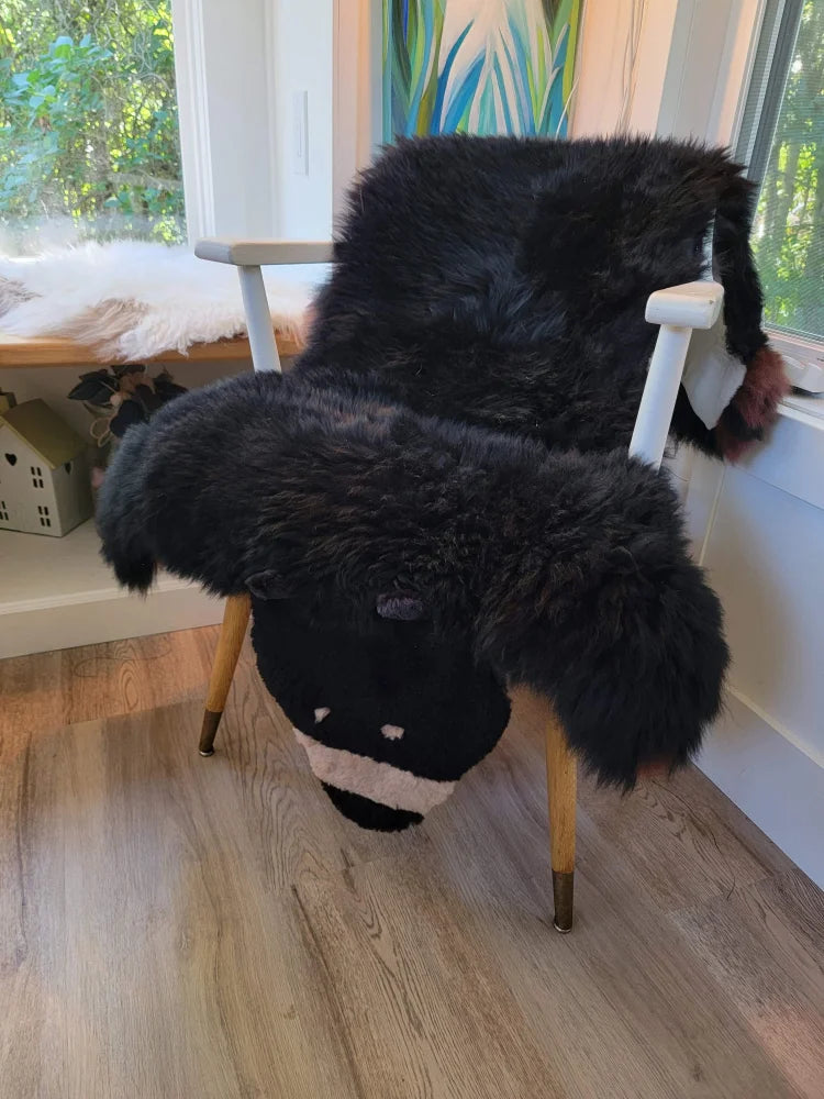 Adorable black bear rug shaped like a fluffy sheep chair cover made of soft merino sheepskin with wooden legs
